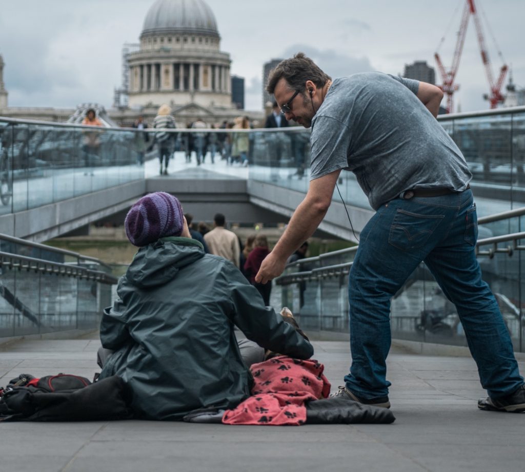 Man handing something to woman sitting on the ground.