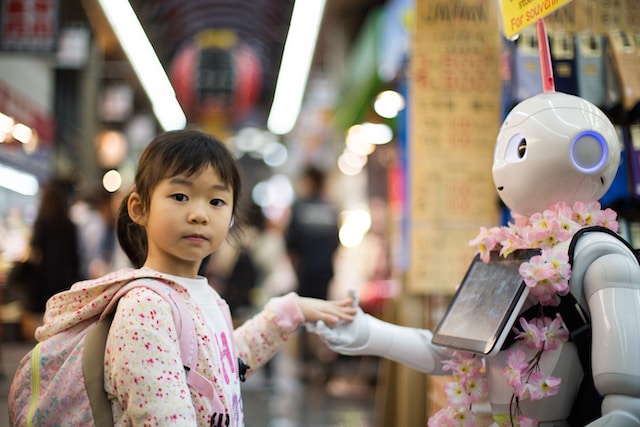Little girl touching hands with cute robot. She has found a new friend.